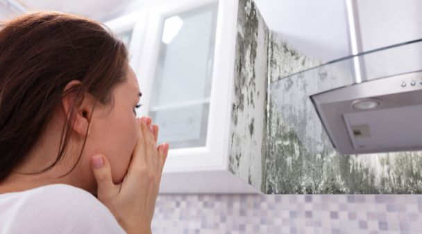 person blocking their nose and looking at black mold